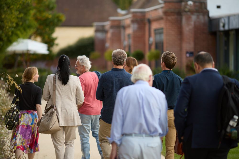 people walking in the grounds of kellogg college with their backs to us with the buildings in the back ground and gardens around them