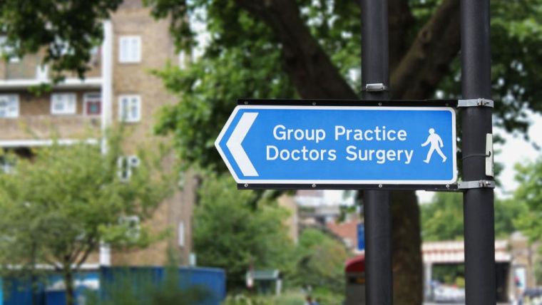 Photo of a street signpost pointing left, reading 'Group Practice Doctors' Surgery'